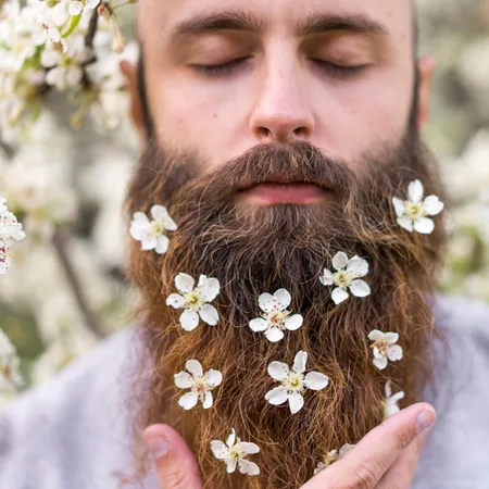Bearded gentlemen in a sleeping pose with flowers in his beard
