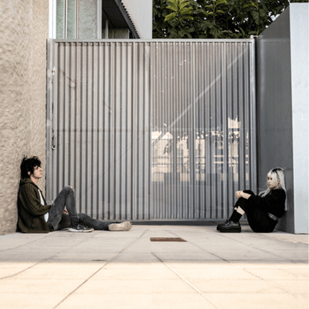 2 people sat on either site of a gated fence