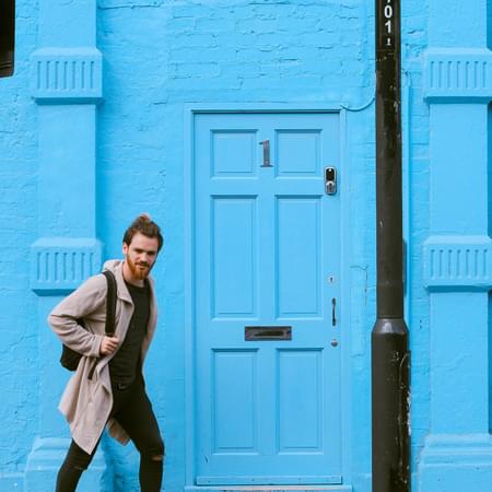 blue house with large number 1 and male with a smart doorbell