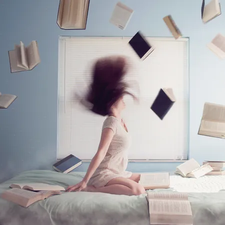 Girl throwing hair back surrounded by books