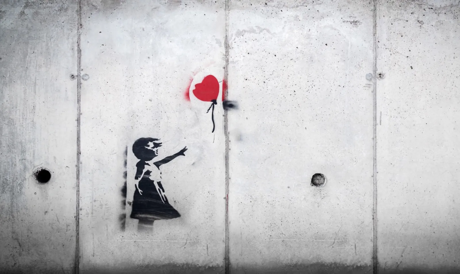 Gray wall with a silhouette of a girl losing a red balloon