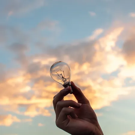 hand-holding-lightbulb-in-front-of-sky