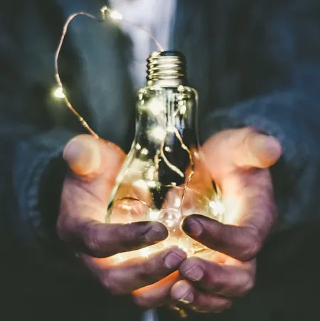 hands-holding-lightbulb-filled-with-fairy-lights