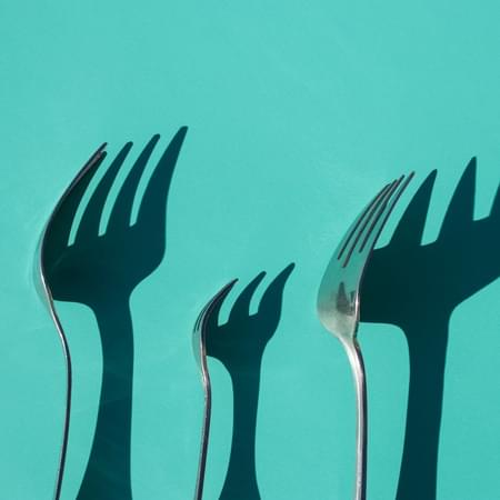 three forks in front of teal background