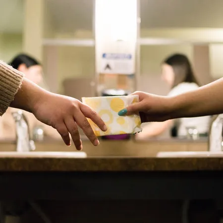 two hands passing sanitary products