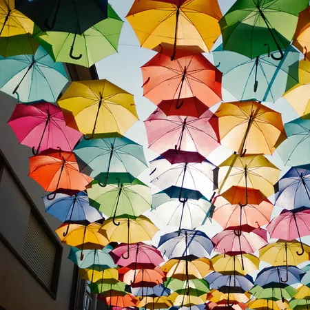 a collection of multi coloured umbrellas hung in between a street