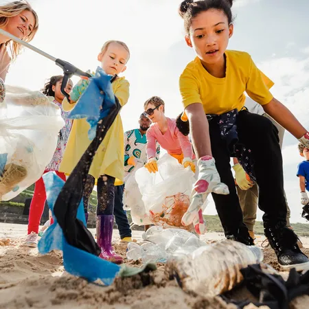 Kids walking on the beach picking up plastic